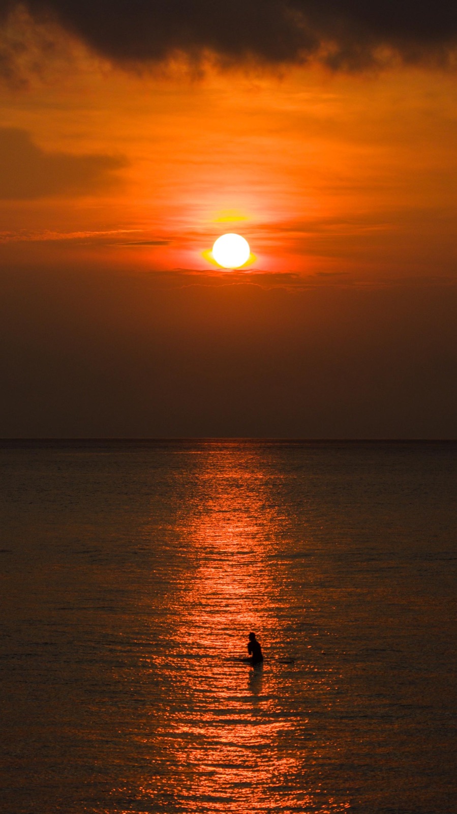 Silhouette of a person swimming at sunset, Mentawai Islands